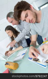 male student with others writing notes in the classroom