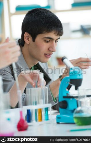 Male student working with microscope and different liquids in school, college or university laboratory
