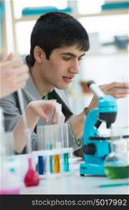 Male student working with microscope and different liquids in school, college or university laboratory