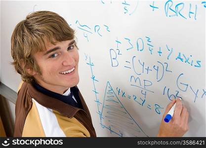 Male student writing maths equations on whiteboard