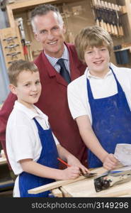 Male students reviewing woodworking plans with teacher