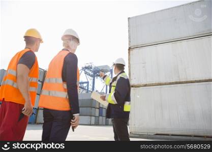 Male supervisor discussing with workers in shipping yard
