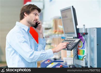 male supervisor looking at clipboard while talking on mobile phone