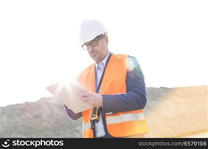 Male supervisor reading clipboard at construction site on sunny day