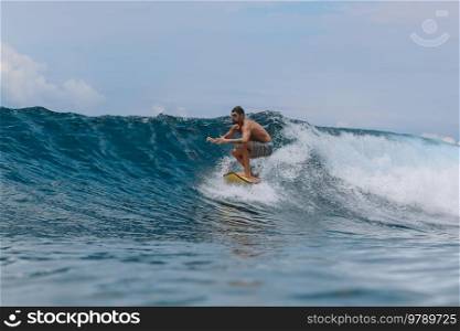 Male surfer on a blue wave at Bali island