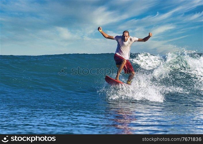 Male surfer on a blue wave at sunny day