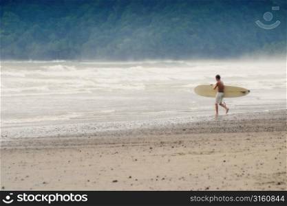 Male surfer walking towards the water