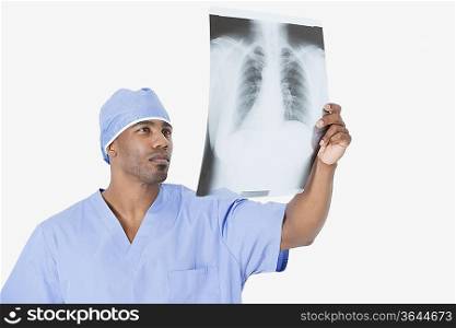 Male surgeon analyzing x-ray report over gray background