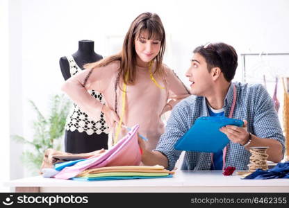 Male tailor with female student in workshop