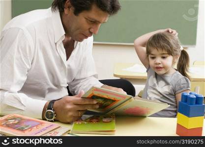 Male teacher teaching his student in a classroom