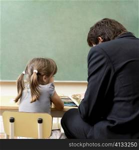 Male teacher teaching his student in a classroom