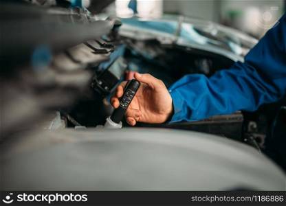 Male technician checks brake fluid level in car. Auto-service, vehicle maintenance, repairman with tools. Male technician checks brake fluid level in car