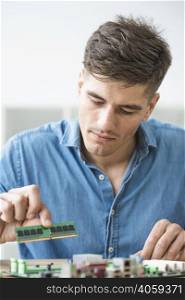 male technician installing ram computer motherboard
