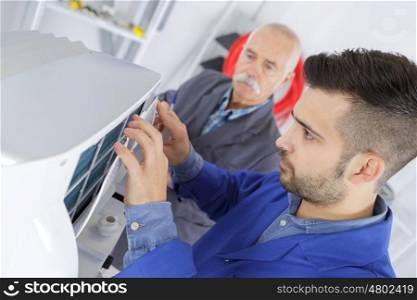 male technician is repairing a printer assited by senior