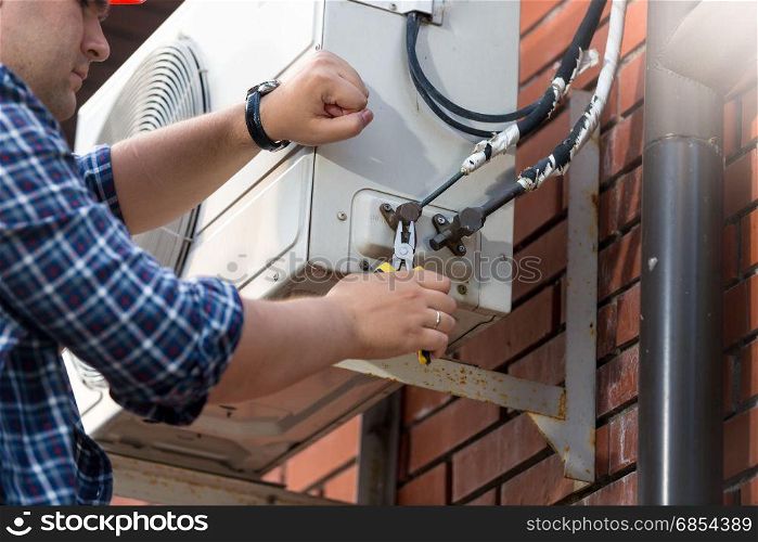 Male technician repairing outdoor air conditioner unit