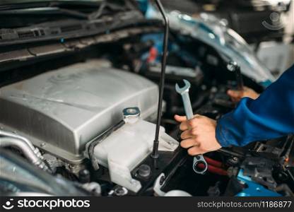 Male technician works with car engine. Auto-service, vehicle maintenance, repairman with tools. Male technician works with car engine