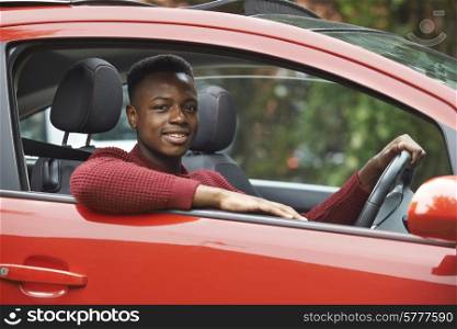 Male Teenage Driver Looking Out Of Car Window