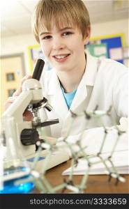 Male Teenage Student In Science Class Looking Through Microscope