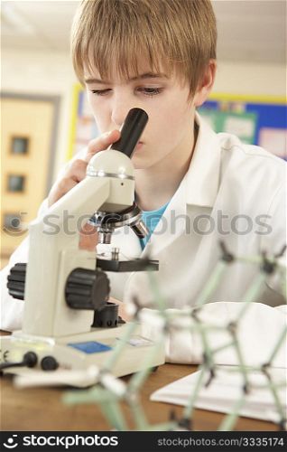 Male Teenage Student In Science Class Looking Through Microscope
