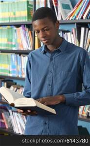 Male Teenage Student Reading Book In Library