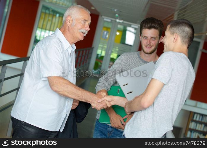 male teenage student shaking hand with teacher