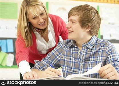Male Teenage Student Studying In Classroom With Teacher