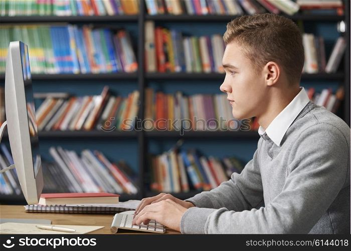 Male Teenage Student Working At Computer In Library