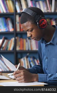 Male Teenage Student Working At Computer Wearing Headphones