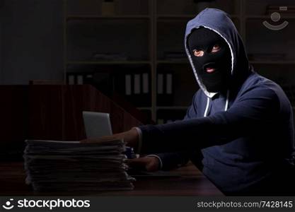 Male thief in balaclava in the office night time 