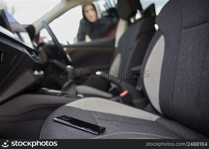 Male Thief Looking Through Car Window At Mobile Phone Left On Seat