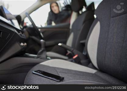Male Thief Looking Through Car Window At Mobile Phone Left On Seat