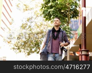 Male tourist in city. Happy male tourist in casual clothes in city walking