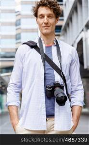 Male tourist in city. Happy male tourist in casual clothes in city with camera