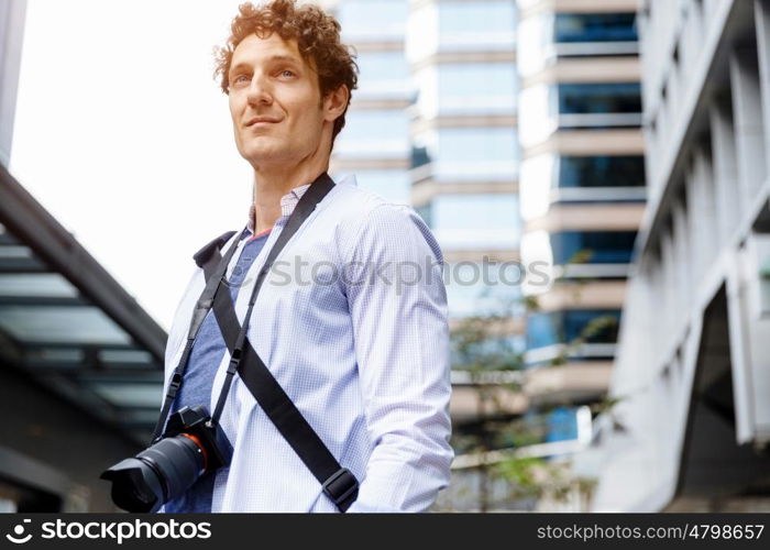 Male tourist in city. Happy male tourist in casual clothes in city with camera