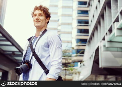 Male tourist in city. Happy male tourist in casual clothes in city with camera