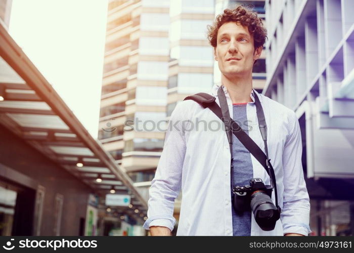 Male tourist in city. Happy male tourist in casual clothes in city with camera