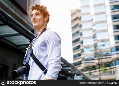 Male tourist in city. Happy male tourist in casual clothes in city with camera