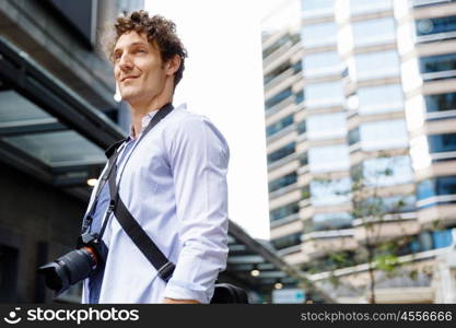 Male tourist in city. Happy male tourist in city walking with camera