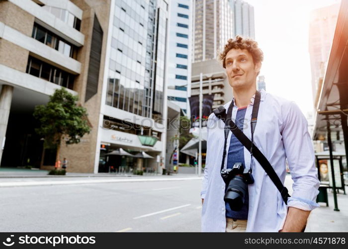 Male tourist in city. Happy male tourist in city walking with camera