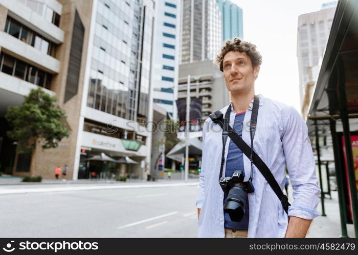 Male tourist in city. Happy male tourist in city walking with camera