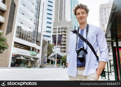 Male tourist in city. Happy male tourist in city walking with camera