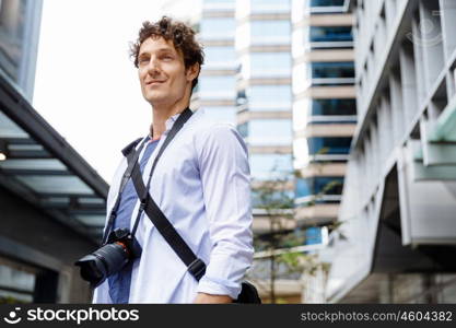 Male tourist in city. Happy male tourist in city walking with camera