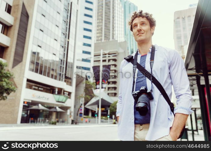 Male tourist in city. Happy male tourist in city walking with camera