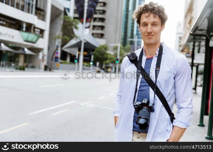 Male tourist in city. Happy male tourist in city walking with camera