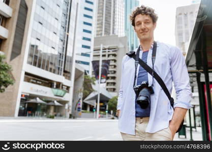 Male tourist in city. Happy male tourist in city walking with camera