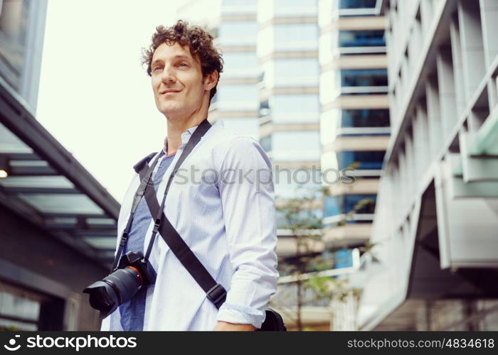 Male tourist in city. Happy male tourist in city walking with camera