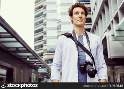 Male tourist in city. Happy male tourist in city walking with camera