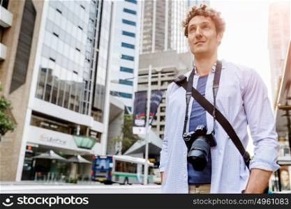 Male tourist in city. Happy male tourist in city walking with camera