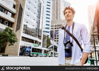 Male tourist in city. Happy male tourist in city walking with camera