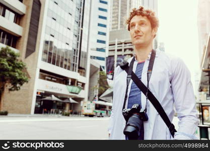 Male tourist in city. Happy male tourist in city walking with camera